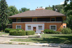 Distant front view of the Winslow House, designed by Frank Lloyd Wright, highlighting its iconic symmetrical design and restored masonry details.
